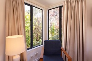 Ein Zimmer mit Ecke und Fenster, einer Lampe und einem Sessel.