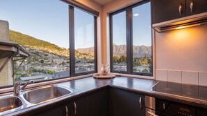 Een moderne keuken met een groot raam met uitzicht op een bergachtig landschap.