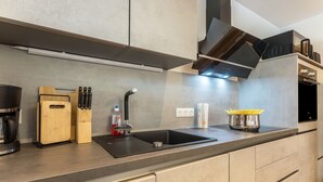 Une cuisine moderne dotée d’un évier encastré, d’appareils électroménagers en acier inoxydable et de planches à découper en bois.