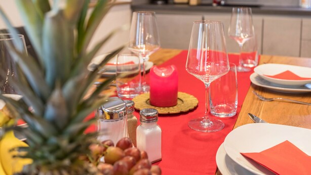 Une table à manger avec des assiettes, des verres, une bougie et des condiments.