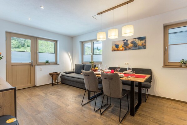 A modern dining area with a wooden table, grey chairs, and pendant lighting.