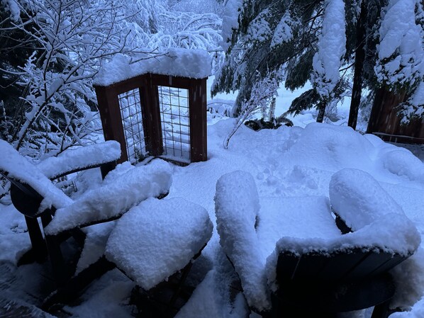 A snow-covered gazebo with a grid-like window design, surrounded by snow-laden trees and a wooden fence. - Li'l Finch Mt. Rainier tiny cabin with covered Hot tub and steam sauna (Ashford)