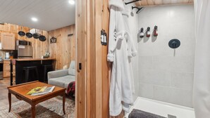 Un intérieur moderne avec un mur en bois, une baignoire blanche et un coin cuisine équipé d’un four à micro-ondes et d’une cuisinière.