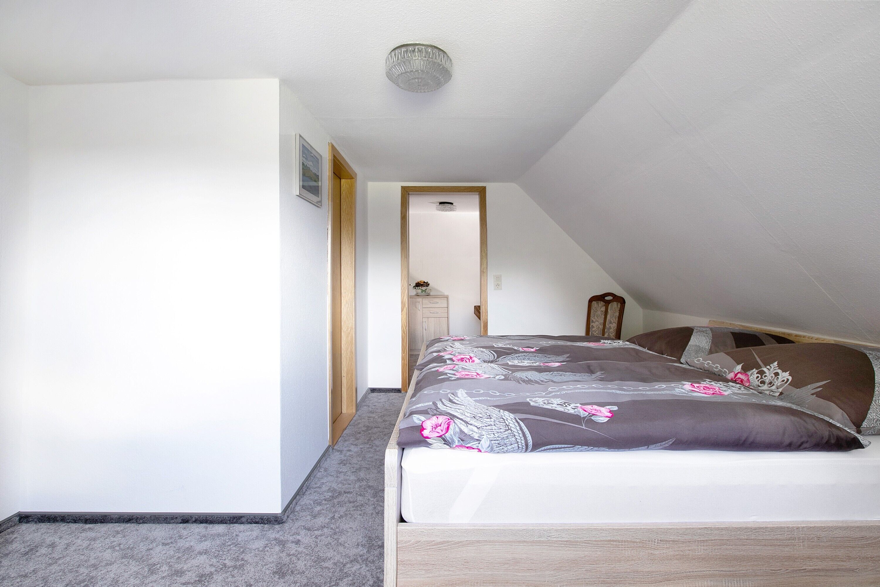 Un dormitorio con cama, una puerta y una lámpara en el techo.