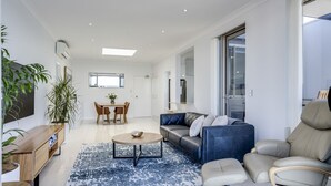 A spacious living area with a sofa, coffee table, and a dining table with chairs.