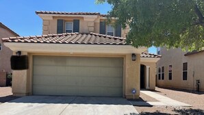 A single-story house with a beige garage door, a small attached garage, and a tree in front.