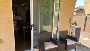 A patio area with two wicker chairs and a sliding glass door leading to a dining area.