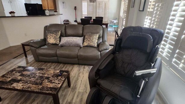 A living room with a sofa, a massage chair, and a coffee table.
