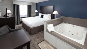 Hotellihuone, jossa on suuri sänky, erillinen oleskelualue, työpöytä ja erillinen kylpyhuone, jossa on kylpyamme.