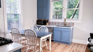 Una cucina con tavolo e sedie, forno a microonde e mobili.