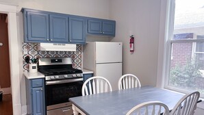 Una cucina con mobili blu, un fornello, un frigorifero e un tavolo da pranzo con sedie.