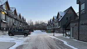 Eine schneebedeckte Straße gesäumt von mehrstöckigen Gebäuden, einige mit Balkonen und großen Fenstern.
