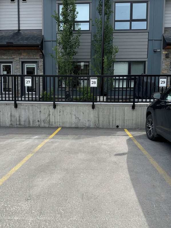A parking area with reserved parking signs numbered 27, 28, and 29, and a concrete barrier.