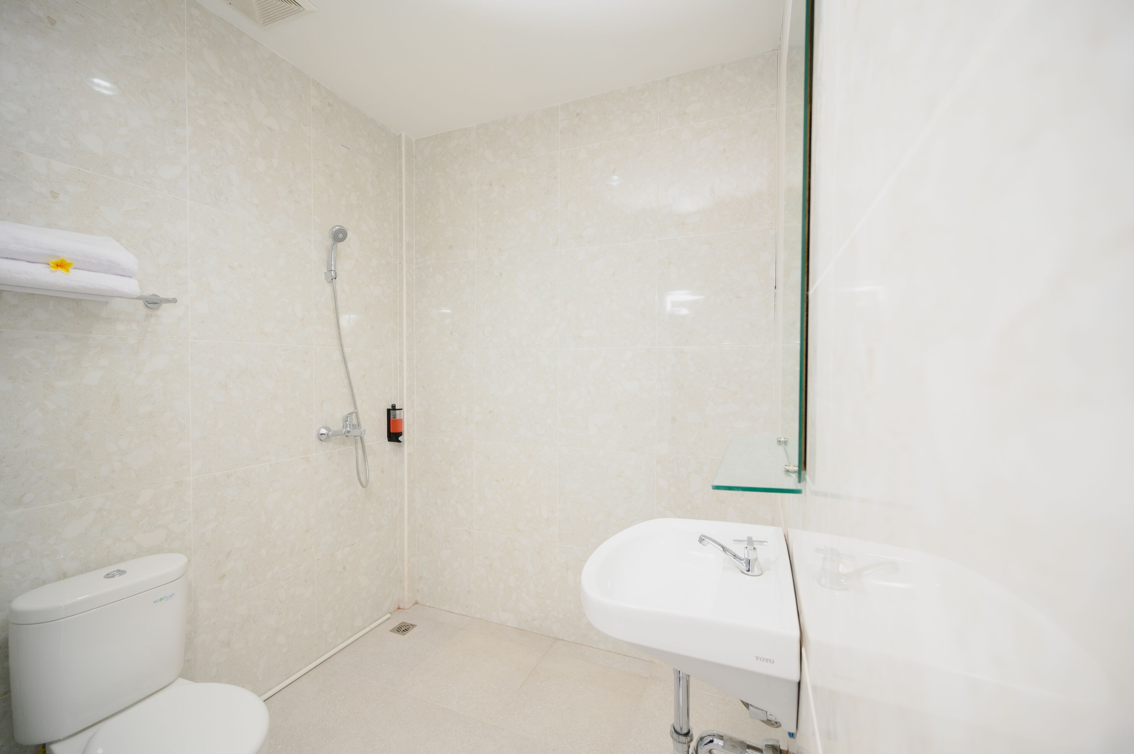 Een moderne badkamer met toilet, douche en wastafel.