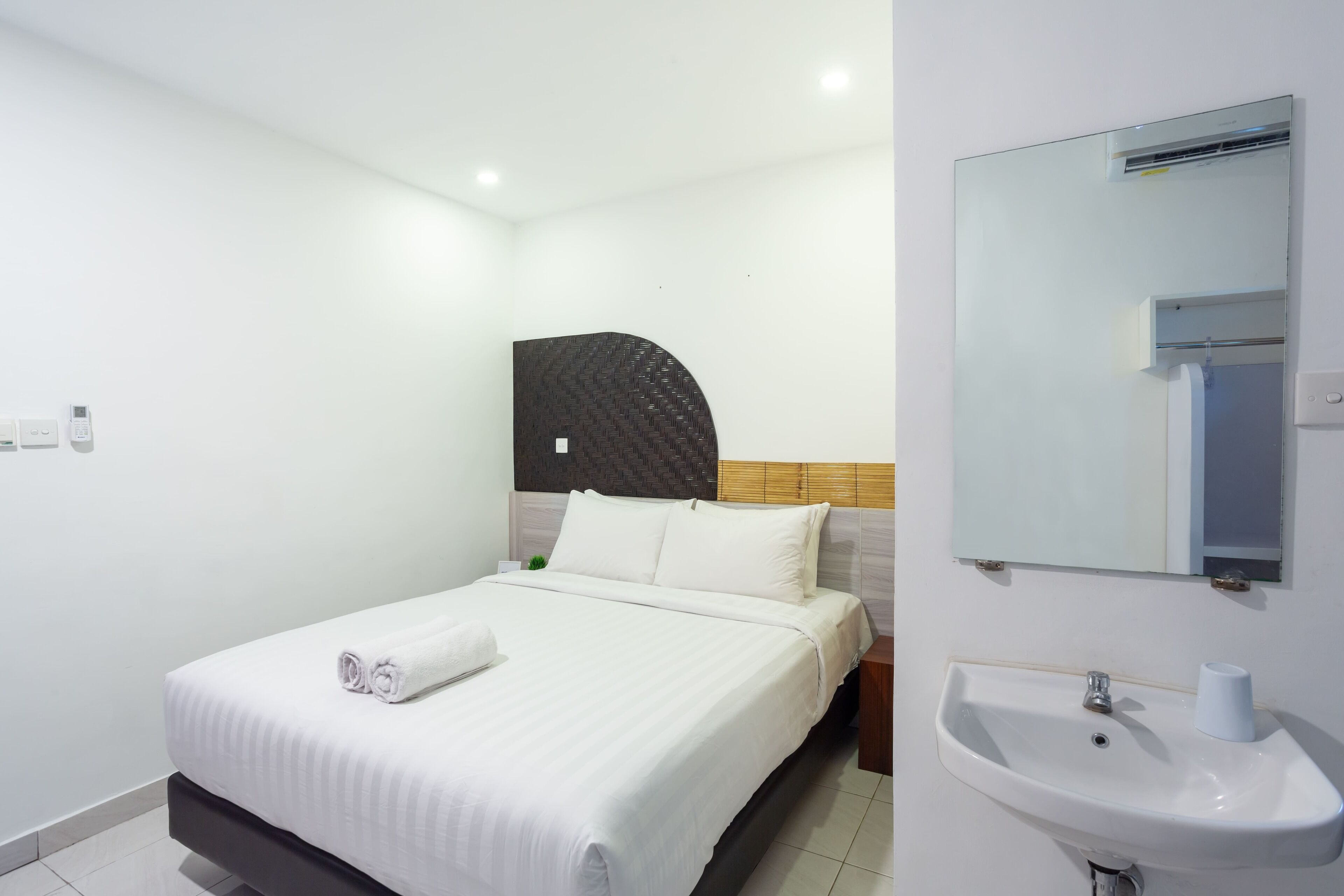 A hotel room with a bed, a white sink, and a mirror.