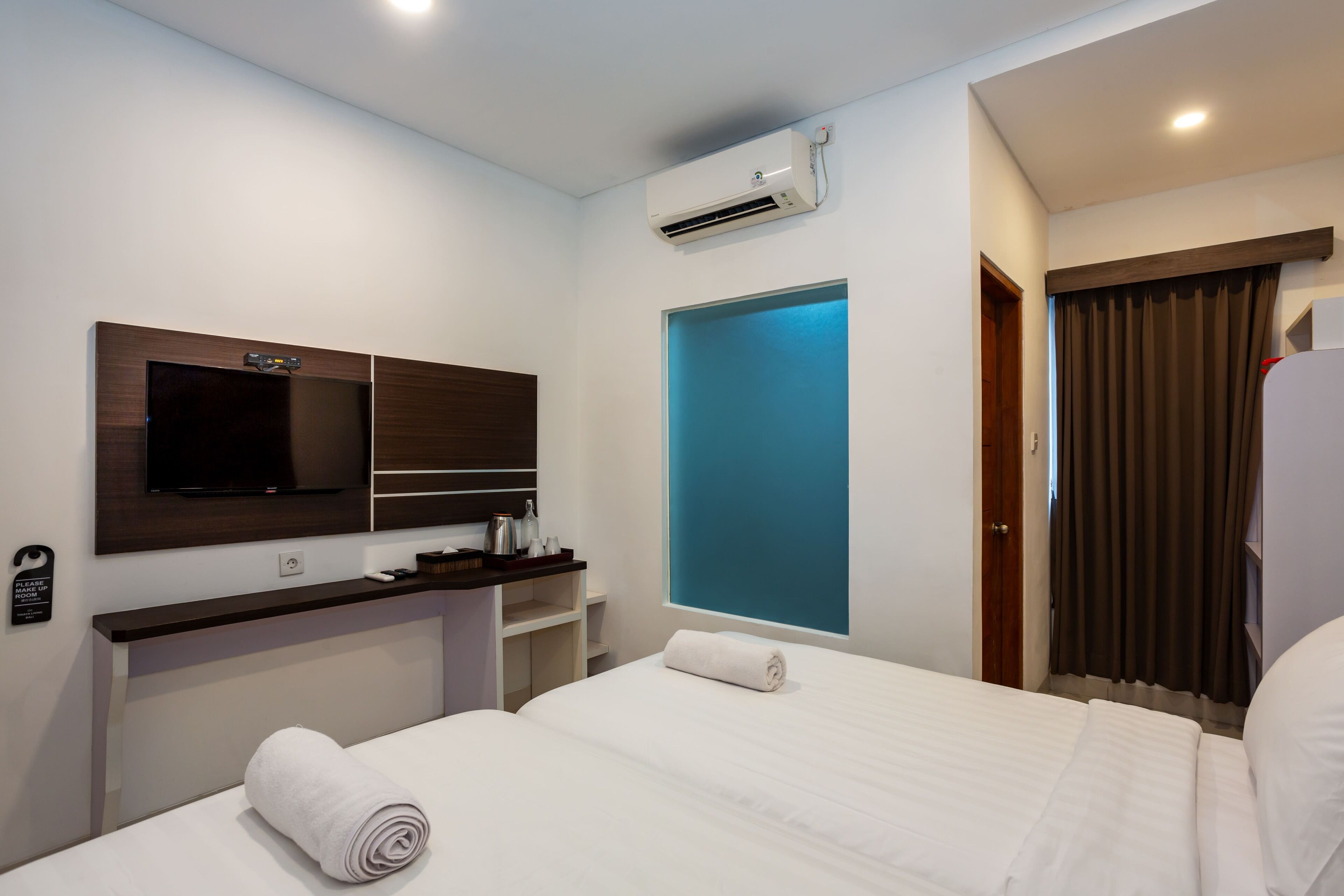 A hotel room with a bed, a TV, a desk, and a bathroom door.