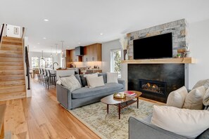Una sala de estar moderna con chimenea, un comedor y una cocina.
