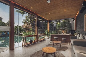 Un interior moderno con piscina, muebles de madera y grandes ventanales.