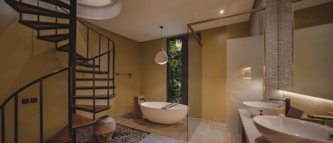 A modern bathroom with a spiral staircase, a freestanding bathtub, and two large sinks.