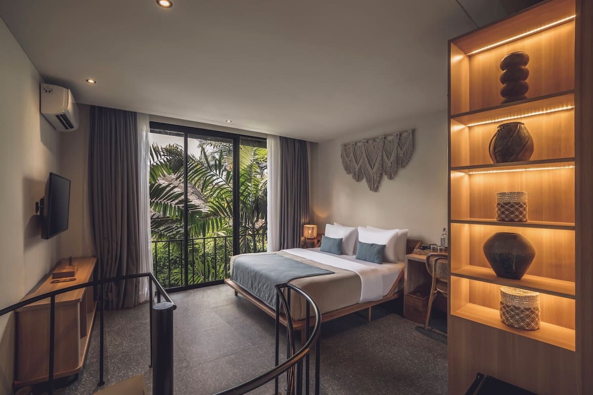 Ein Hotelzimmer mit einem großen Bett, einem Schreibtisch mit Stuhl, einem Fernseher und einem Regal mit Dekoration.