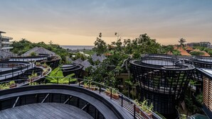 Un moderno resort con estructuras circulares, abundante vegetación y vistas al océano.