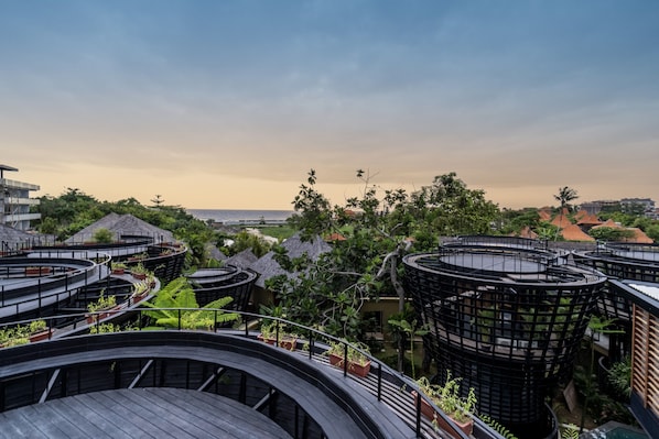 Un complexe hôtelier moderne doté de bâtiments à structure circulaire, d’une végétation luxuriante et offrant une vue sur l’océan.