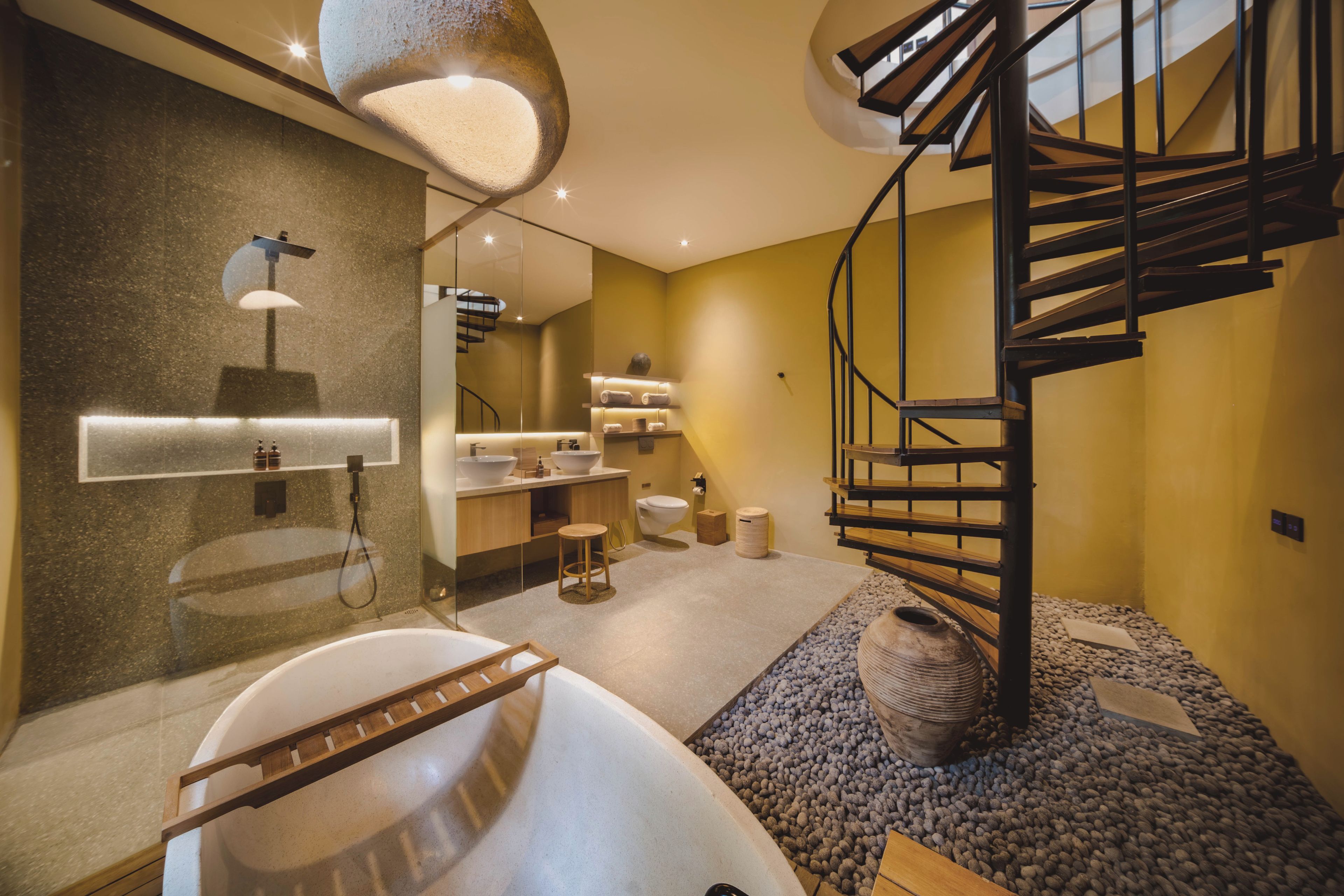 Une salle de bain moderne avec une baignoire, une échelle en bois, un grand miroir et un escalier en colimaçon.