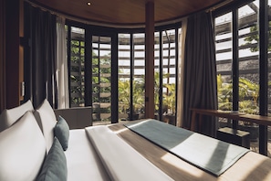 A modern hotel room with a large bed, a view of greenery through large windows, and a wooden ceiling. - Canggu Cabana Beach Resort by Ini Vie Hospitality (Canggu)