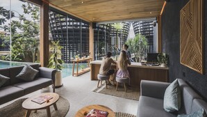 Una sala de estar moderna con piscina, un sofá, una mesa de centro y un escritorio donde dos personas trabajan.