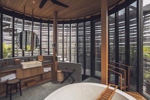 A modern bathroom with a large mirror, wooden vanity, and a view of the outdoors through large windows. - Canggu Cabana Beach Resort by Ini Vie Hospitality (Canggu)