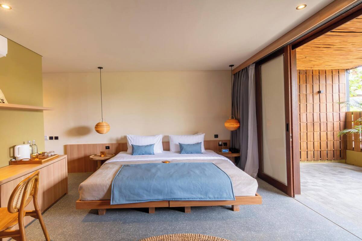 Ein modernes Hotelzimmer mit Bett, Schreibtisch, Stuhl und Blick ins Freie.