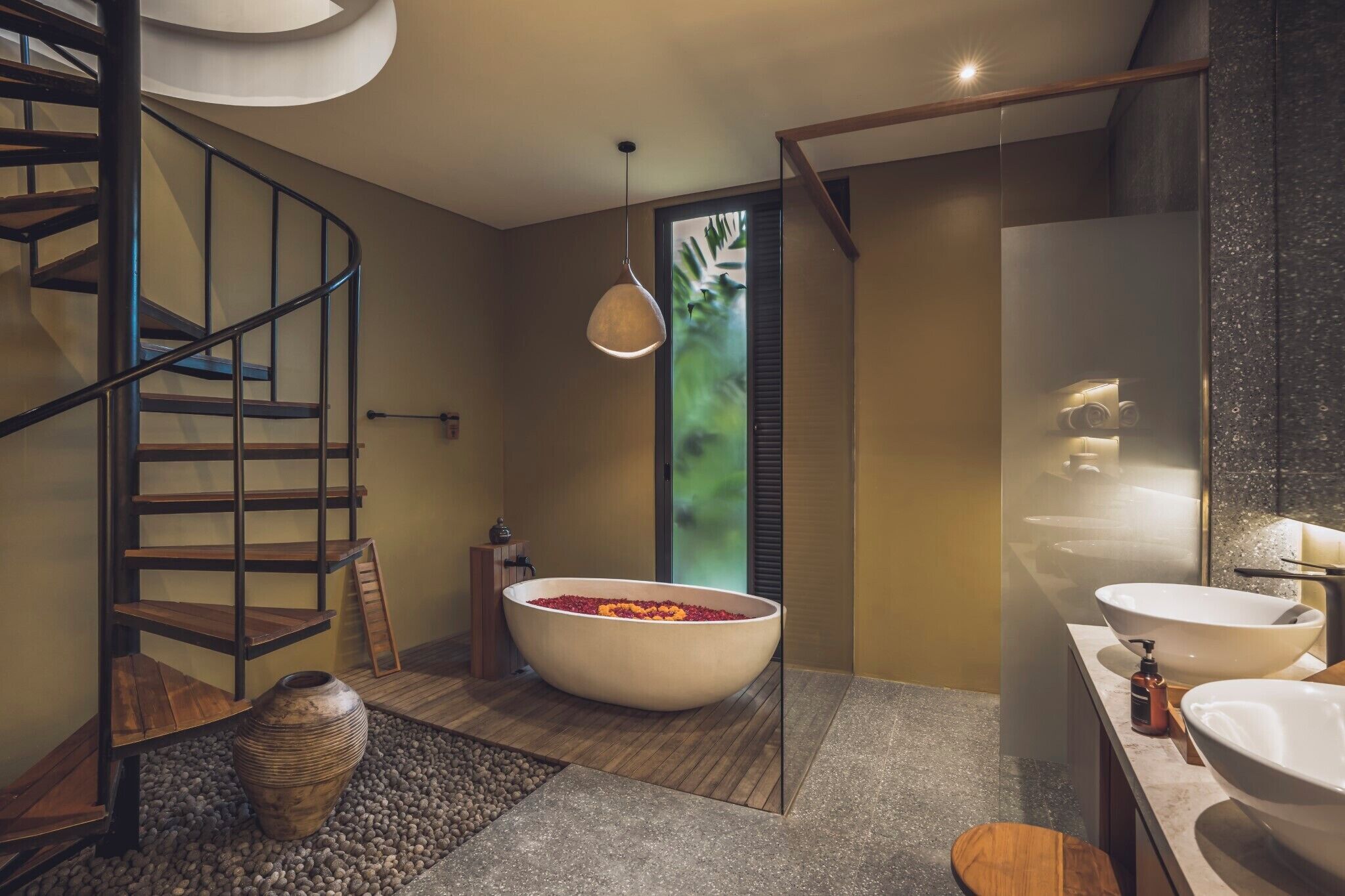 A modern bathroom with a freestanding bathtub, a wooden spiral staircase, and a large mirror.