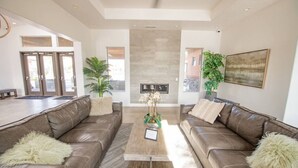 A spacious living room with two leather sofas, a coffee table, and a fireplace. - Spacious Oasis, Private Pool, Spa & Putting Green (Hurricane)