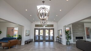A spacious lobby with a modern chandelier, a reception desk, and a seating area with a bench and sofa. - Spacious Oasis, Private Pool, Spa & Putting Green (Hurricane)