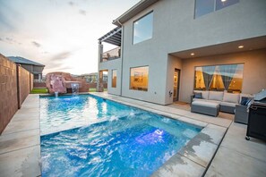 Et moderne hus med swimmingpool, udendørs møbler og et vandfald.