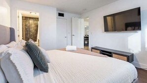 Un dormitorio moderno con una cama grande, un televisor montado en la pared y un vestidor.