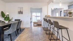Una cocina moderna con comedor, que cuenta con una encimera larga, taburetes de bar y vistas al exterior.