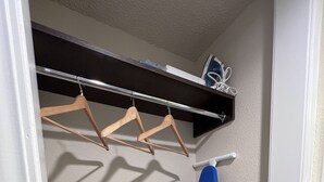A closet with wooden hangers, a blue ironing board, and a white wall. - Mod KING Studio Apartment w/private covered patio (Southfield)