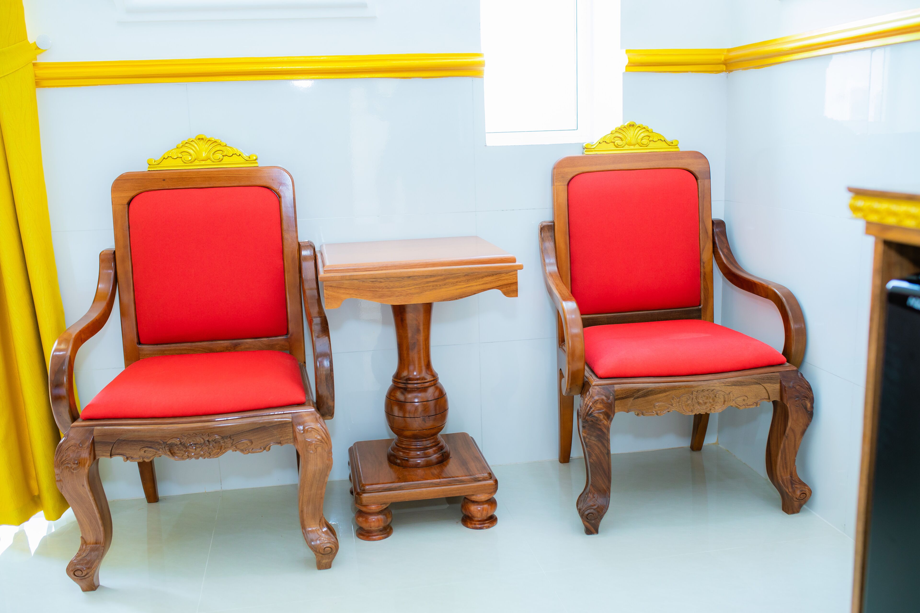 Dos sillas de madera con cojines rojos y una pequeña mesa de madera entre ellas.
