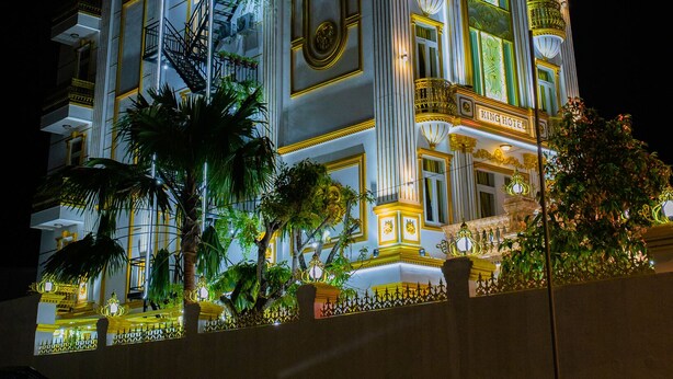 A multi-story hotel with a prominent "King Hotel" sign, ornate architectural details, and a well-lit facade.