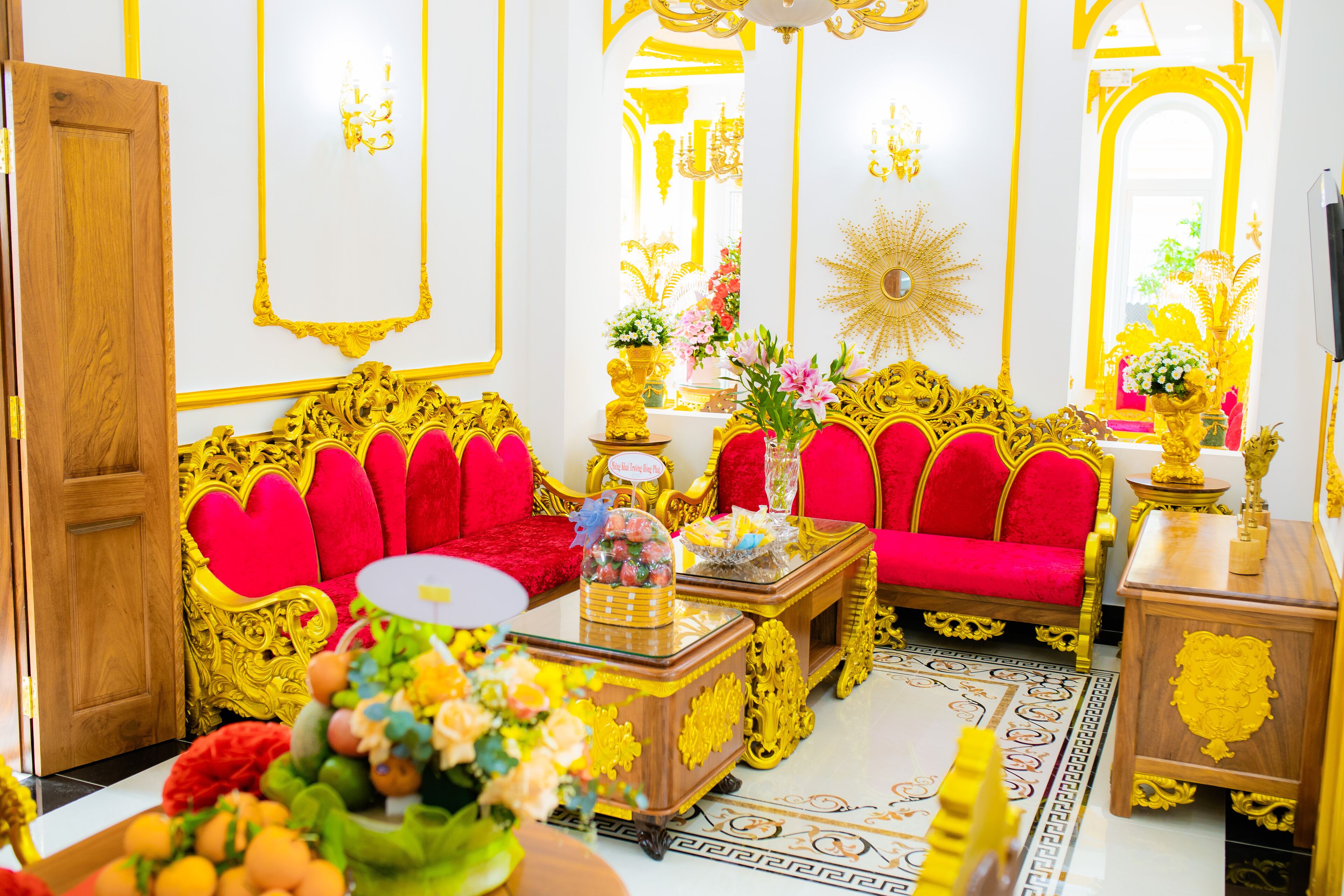 A luxurious room with ornate golden furniture, red upholstered sofas, and a decorative mirror.