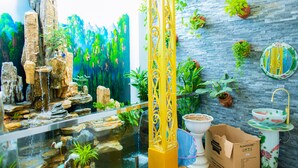 A room with a large aquarium, a decorative column, and a wall-mounted sink with a floral design.