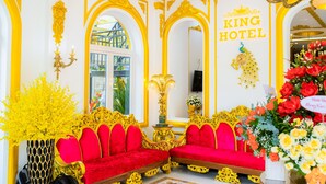 A luxurious room with a red sofa set, ornate gold detailing, and a 'King Hotel' sign.