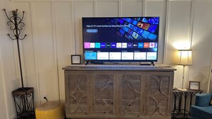 A flat-screen TV on a wooden cabinet with a network settings screen, a lamp, and a framed quote on the wall. - Shalom Abode - Country Experience in the City! (Levelland)