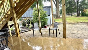A covered patio area with a concrete floor, two wicker chairs, a small round table, and a birdhouse. - 1st Floor Condo: Min to Nook, Amish Ctry, Hershey, Lancaster City: PetFriendly (Lancaster)
