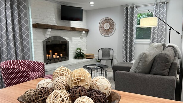 A living room with a fireplace, a television mounted on the wall, and a table with decorative items. - 1st Floor Condo: Min to Nook, Amish Ctry, Hershey, Lancaster City: PetFriendly (Lancaster)