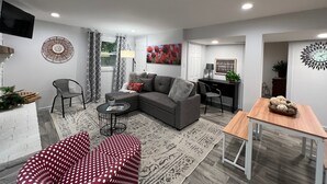 A modern living room with a grey sectional sofa, a red polka dot chair, a small round table, and a wooden side table. - 1st Floor Condo: Min to Nook, Amish Ctry, Hershey, Lancaster City: PetFriendly (Lancaster)