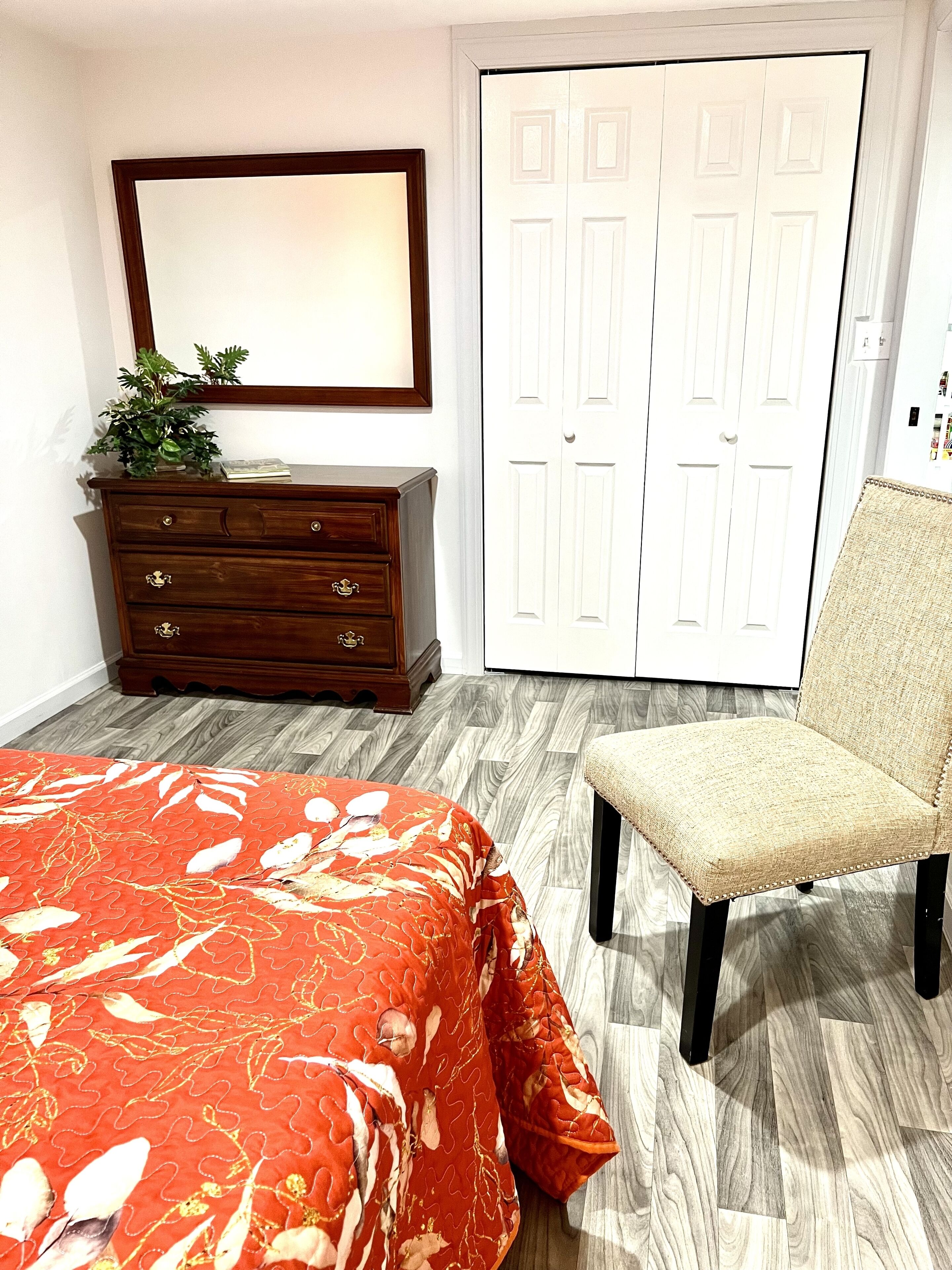 Une chambre à coucher avec un lit, une commode, une chaise et un placard blanc.