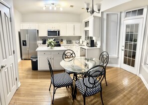 Kitchen features a microwave, coffee maker, and glass-top dining table with two chairs.