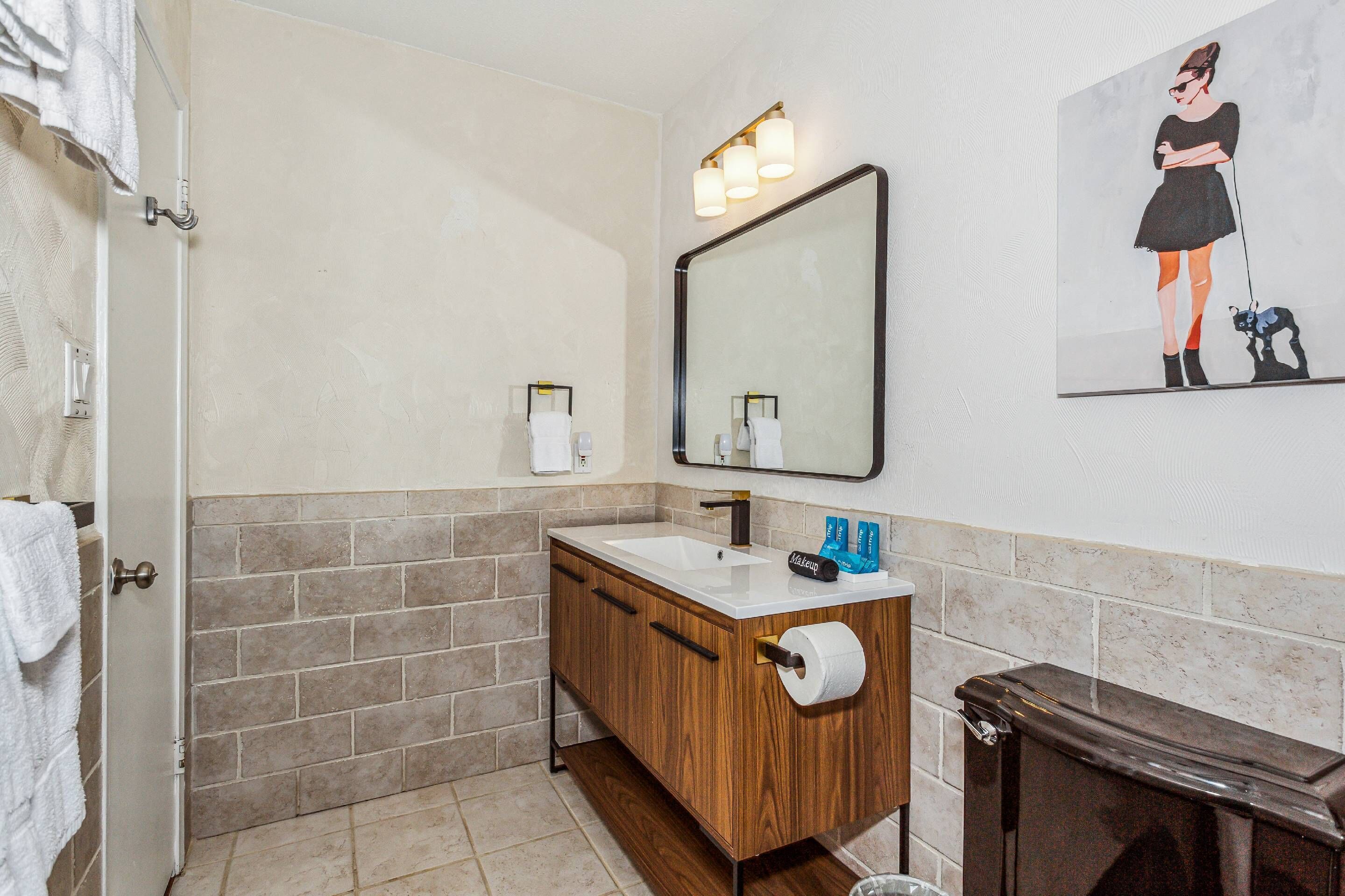 Une salle de bain avec un meuble-lavabo en bois, un grand miroir et une serviette accrochée à la porte.